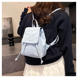 Close-up of light blue backpack featuring unique crinkled texture and drawstring closure