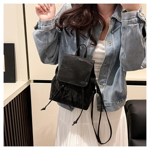 Detail of a vintage black pleated PU leather backpack styled with a denim outfit