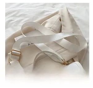 Detail of white crossbody bag featuring red cherry prints and a wide adjustable shoulder strap