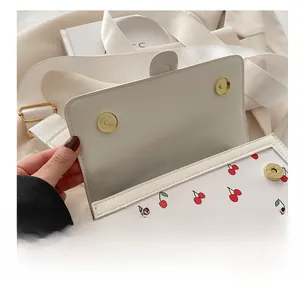 Detail shot of the dual metal magnetic snaps on a white cherry print crossbody bag