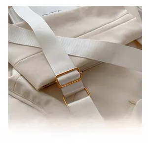 Detail of adjustable gold-tone metal buckle on white woven crossbody bag strap