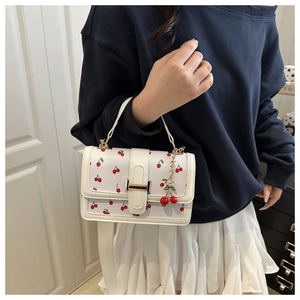 Détail du sac blanc à motif cerises, fermoir doré et pendentif cerise assorti