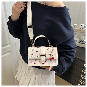 White leather handbag with cherry pattern and wide shoulder strap shown on a model