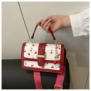 Dettaglio della mini borsa a tracolla bianca con stampe ciliegia e bordi in pelle rossa