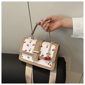 Dettaglio della piccola borsa bianca a ciliegie con fibbia dorata e ciondolo a ciliegia