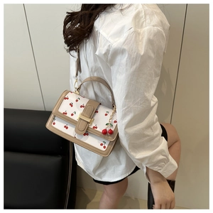 Dettaglio borsa bianca con stampa ciliegie, finiture marroni e charm ciliegia 3D