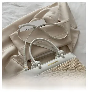Detail der Strohtasche mit cremefarbenem Lederbesatz und goldenem Fashion-Schriftzug