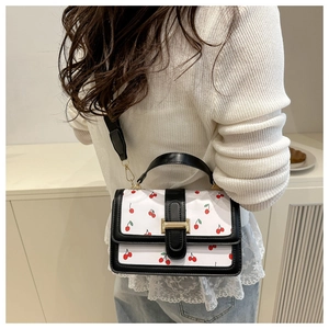 Detailed view of cherry print handbag showing the gold clasp and black leather accents