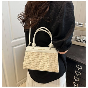 Detail of fashion crossbody bag with woven straw base and white leather top stitching
