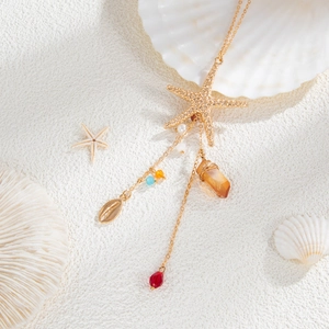Detail of starfish pendant with seashells, colored beads, and crystals on sandy beach background
