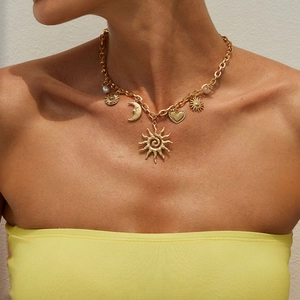 Close-up of golden multi-pendant chunky chain with sun, moon, and heart charms