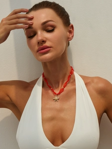 Dettaglio di un ciondolo a stella marina dorata su collana in nastro di seta rossa e oro