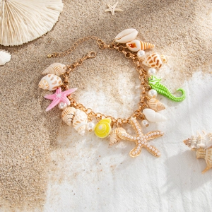 Macro view of gold chain belt featuring pearl starfish, colorful seahorse and shell pendants