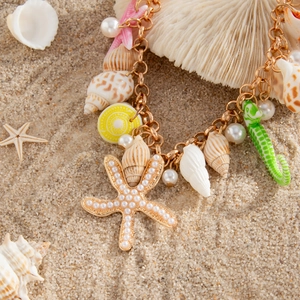 Detailed shot of starfish and seashell waist chain on sand for summer beach styling