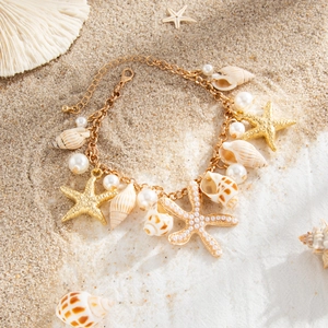 Detailed macro view of golden starfish and seashell charms on a pearl body chain