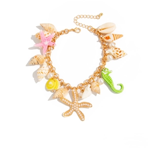 Golden ocean charm bracelet with starfish, seashells, and pearls on a white background
