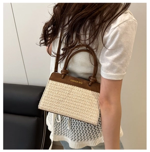 Detail of a large straw tote bag with brown leather trim and FASHION BAG logo