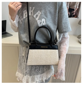 Detail einer Stroh-Handtasche mit schwarzem Lederbesatz und abnehmbarem Schultergurt