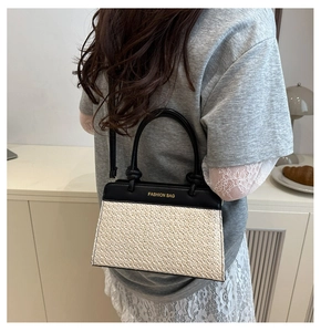 Detailaufnahme der zweifarbigen Strohtasche mit schwarzem Lederbesatz und Goldaufdruck