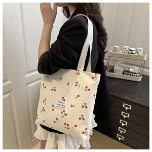 Close-up of model carrying cherry print corduroy tote bag showing large capacity and size