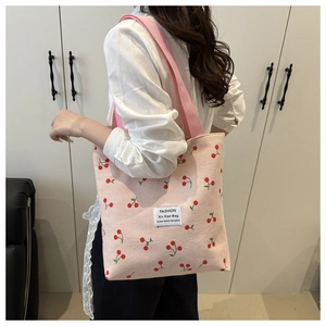Pink corduroy tote bag with cherry pattern detail and fashion tag on model shoulder