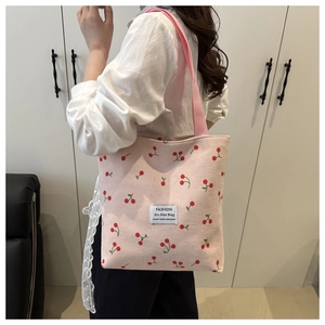 Detail of pink corduroy tote bag featuring cherry patterns and lace trim decoration