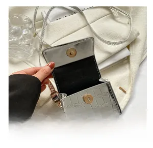 Detail of silver crocodile-embossed mini bag featuring a gold magnetic cylinder clasp