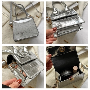 Macro view of silver crocodile pattern mini bag showing golden chain and interior space