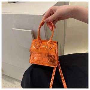 Detailed macro view of bright orange crocodile embossed mini handbag with glossy finish