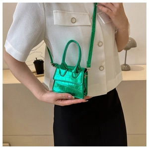 Detail of emerald green mini crossbody bag with crocodile embossing and metallic finish
