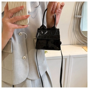 Detail view of mini black faux leather handbag with crocodile pattern and long handle