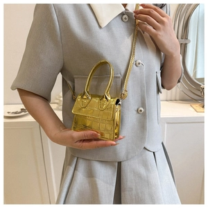 Macro view of metallic gold mini square bag with realistic crocodile pattern details