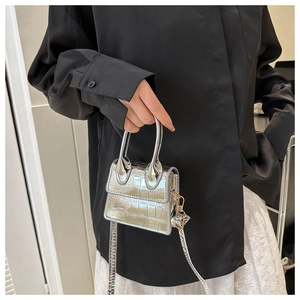 Detailed view of silver mini crossbody bag with crocodile pattern and metal handle
