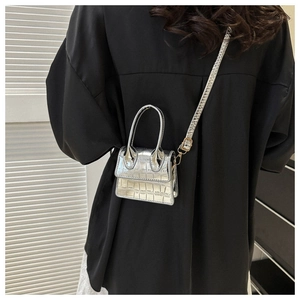 Macro detail of silver croc-embossed mini bag with metallic texture on a black shirt