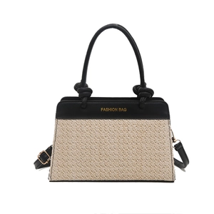 Fashionable minimalist black leather and beige woven straw tote bag with shoulder strap