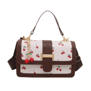 White crossbody bag with cherry prints, brown leather trim and golden clasp