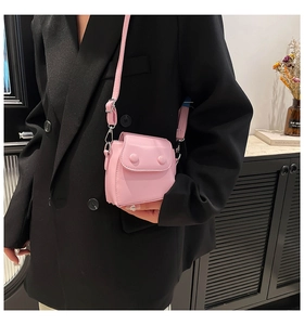 Pink mini crossbody bag styled on a black blazer showing compact size and silver hardware
