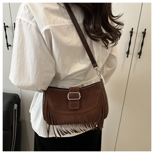 Détail du sac à bandoulière en daim marron foncé à franges au style bohème et vintage