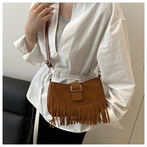 Détail d'un sac bandoulière en daim marron avec des franges bohèmes et boucle en métal