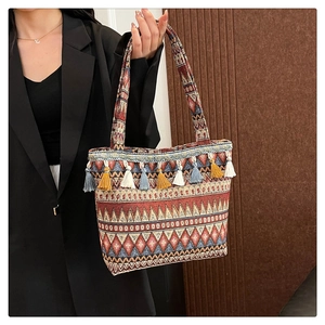 Detailed macro view of woven ethnic tote bag with colorful diamond patterns and fringe trim