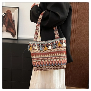 Detailed close-up of ethnic tote bag with colorful geometric weaving and fringe tassels