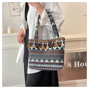 Detail of bohemian woven tote bag with colorful ethnic geometric patterns and silk tassels