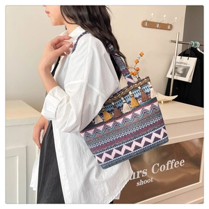 Close-up of ethnic tapestry shoulder bag with colorful tassels and fringe detail