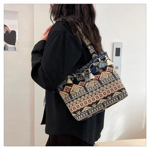 Detailed side view of ethnic canvas tote bag with geometric patterns and colorful tassels