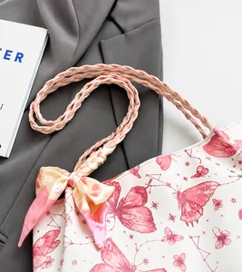 Detail of pink woven shoulder strap and silk bow on white butterfly canvas tote bag