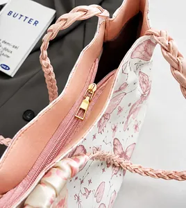 Close-up of smooth gold zipper and pink woven handle on a white butterfly tote bag
