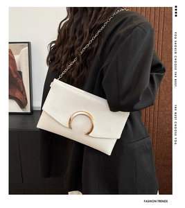 Modern white envelope bag with gold C-shaped metal buckle worn over a black blazer