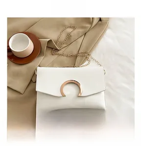 Detailed view of white envelope bag with golden C-buckle next to a smartphone