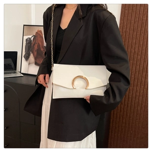 Detail of white envelope bag with gold horseshoe buckle on model with chain strap