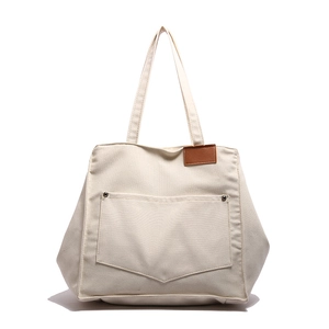 Grande borsa tote in tela crema con tasca frontale e dettaglio in pelle su bianco